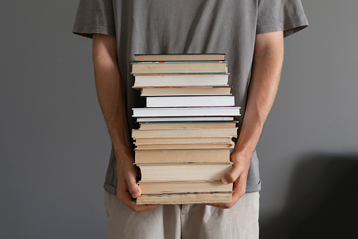 student holding and carrying stack of books