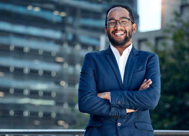 Shot of a young businessman standing with his arms crossed against a city background Everything can be fixed with a smile businessman happiness outdoors cheerful stock pictures, royalty-free photos & images