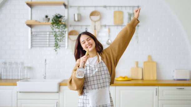 Asian young woman dancing in kitchen room. She happy and relaxing at free time on weekend stock photo