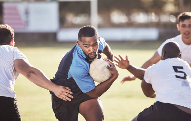 istock African american rugby player running away from an opponent while attempting to score a try during a rugby match outside on a field. Black man making a play to try and win the game for his team 1423804561