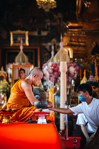 Bangkok, Thailand - August  29, 2022 .Tourist being blessed by buddhist monk inside the beautiful Wat Arun Temple in Bangkok, Thailand.