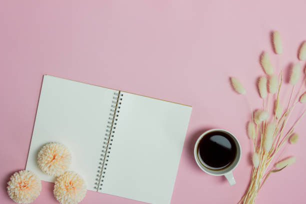 istock White notebook with coffee and flowers over the pink background. 1423823795