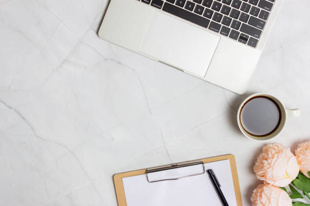 istock Computer with coffee, paper and roses over the marble background. 1423823799