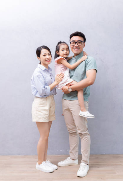istock Young Asian family standing on background 1423826946