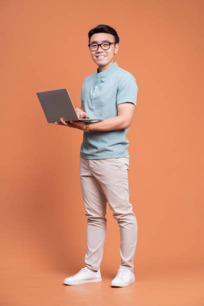 istock Full length image of young Asian man standing on backgound 1423827124