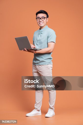 istock Full length image of young Asian man standing on backgound 1423827124