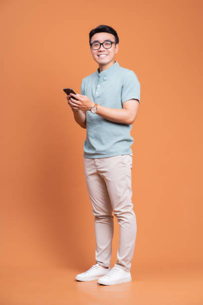 imagen de cuerpo entero de un joven asiático de pie en el backgound - reflection businessman business telephone fotografías e imágenes de stock