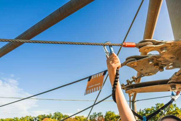 happy woman with sport helmet enjoying zip lining, arms raised.