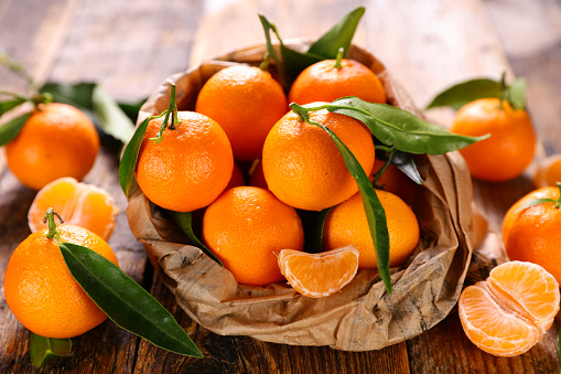 Satsuma Mandarin or tangerines Citrus unshiu. Three whole tangerines citrus fruit in the foreground with one Satsuma Mandarin or tangerines cut in two, placed in the background.