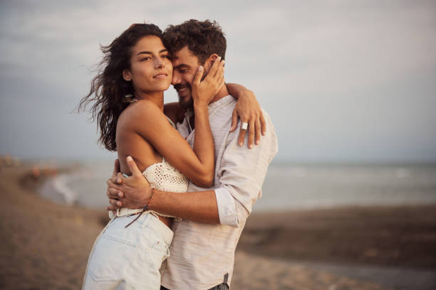 istock Young couple in love standing embraced on the beach. 1423843933