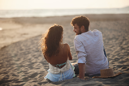 Outdoor shot of romantic young couple together on beach. Young man and woman in love on seashore.