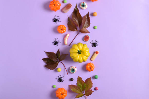istock A mockup with Halloween decorations with pumpkins and sweets on a purple background with a place for text. A place to copy. Flat position, top view 1423846677