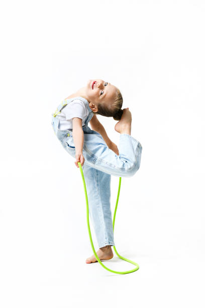 little girl dressed in denim overalls put feet on head with jumping rope. - gymnastics smiling little girls only isolated on white imagens e fotografias de stock