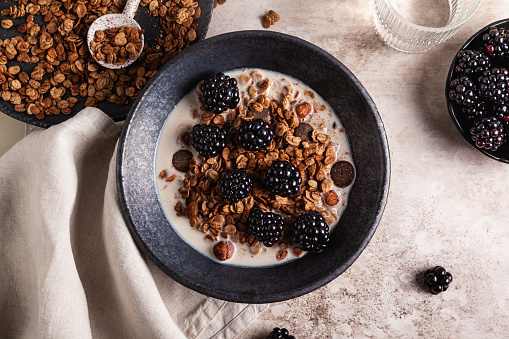 Eating healthy yogurt with cereals and fresh berries like raspberries, blueberries and blackberries