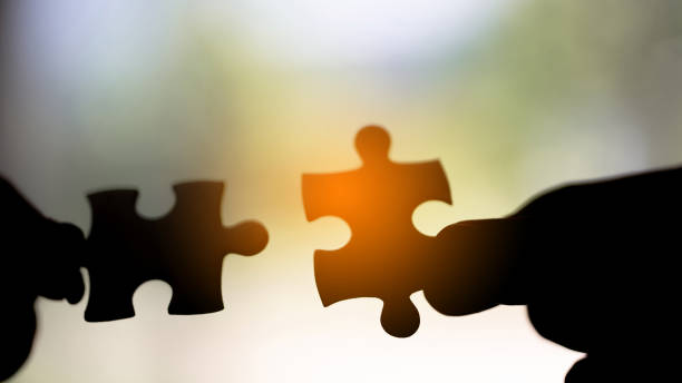 Closeup hand of woman connecting jigsaw puzzle stock photo