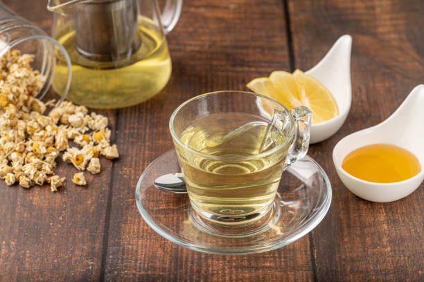 rilassante camomilla in tazza di vetro con fette di limone e miele accanto su tavolo di legno. - homewares rustic herbal tea herb foto e immagini stock