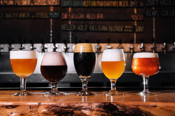 different types of craft beer in glasses on table in pub interior in daylight - lager beer imagens e fotografias de stock