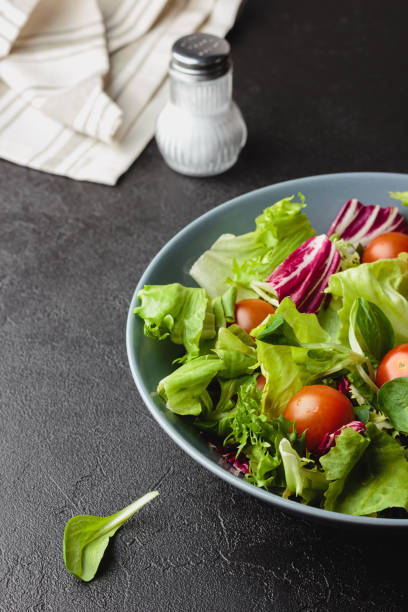 istock Green salad leaves in bowl on black table. 1423854995