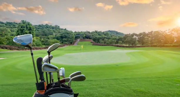 Photo of The Golf club bag for golfer training and play in game with golf course background , green tree sun rays.