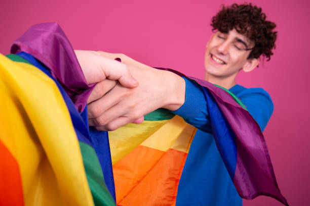 jovem atraente com uma bandeira de arco-íris. - flag gay man american culture rainbow - fotografias e filmes do acervo