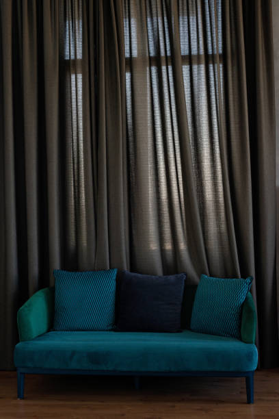 istock Stylish comfortable blue velor sofa with pillows in a modern interior. Soft selective focus. 1423862283