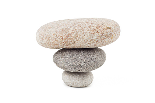 Three stones stacked on a bed of algae overlooking the rocky bay.