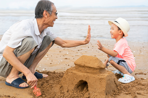 Grandpa and grandson digging sand by the sea