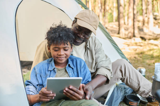 istock Smiling boy in casualwear communicating in video chat while sitting in tent 1423865876