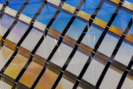 Contemporary architecture. Modern building facade of sports venue with perforated and polished aluminum plates. Texture of metal structures close-up, steel background. Abstract technology.