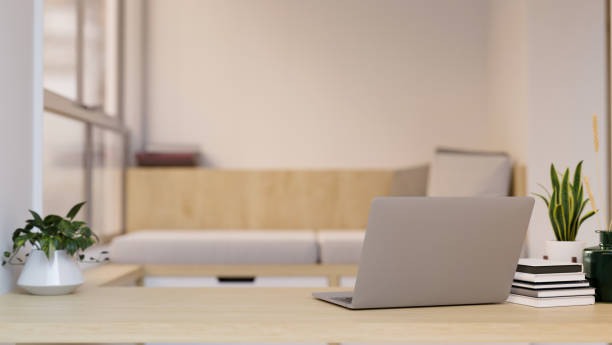 istock Workspace with laptop and copy space on wood tabletop over blurred minimal living room 1423867891