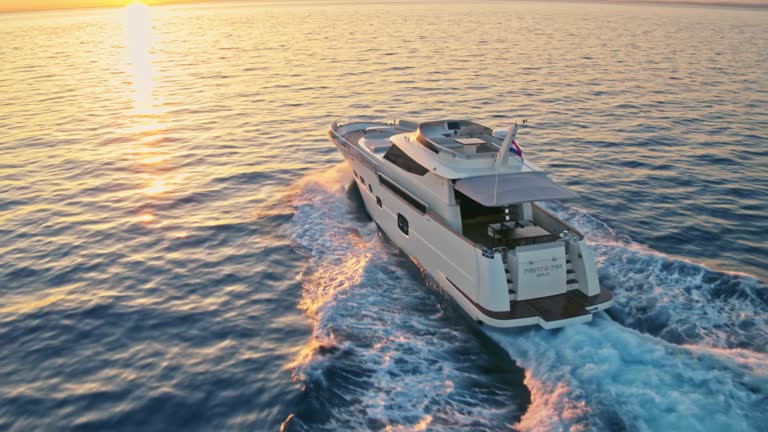 AERIAL Along a yacht travelling the sea at sunset