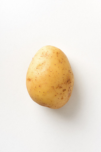 Detail of clean whole potato with skin texture isolated on white table. Top view. Vertical composition.