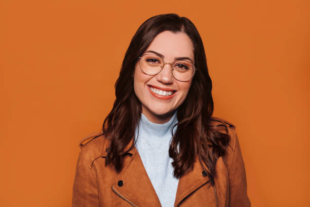 Young cheerful brunette woman in eyeglasses at studio