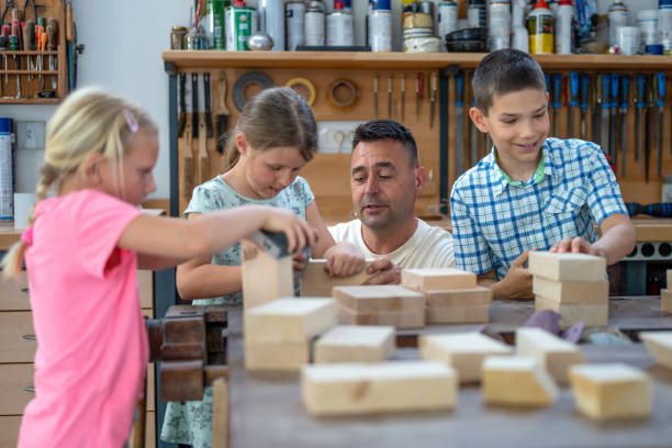 Children with carpenter sanding wooden blocks stock photo