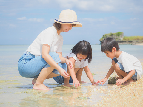 A Japanese family enjoying a holiday with their children at a beach in Okinawa, Japan.