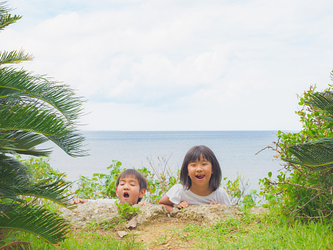 A Japanese brother and sister happily playing together in a park on a holiday.