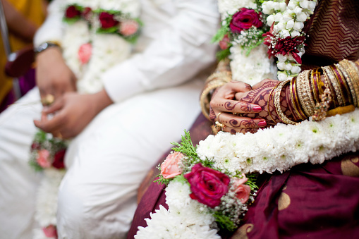 Close-up Indian bride hands with mehndi and bangles during a traditional Hindu wedding, soft focus image.