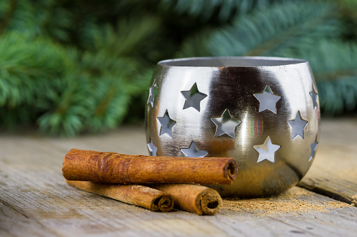 Christmas (New Year) decoration composition. Cinnamon sticks with metal candlestick on wooden background