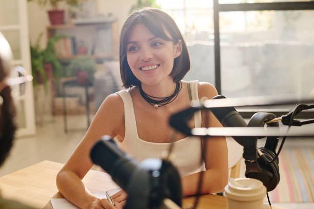 istock Young smiling woman looking at her guest and taking interview for audience 1423887767
