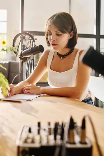 Photo of Young brunette woman in white tanktop looking through her notes in document