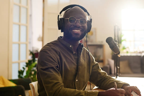 istock Young cheerful black man in headphones looking at camera by workplace 1423888565