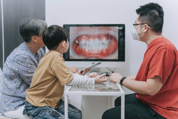 asian chinese male dentist explaining to senior woman and young boy on teeth structure and