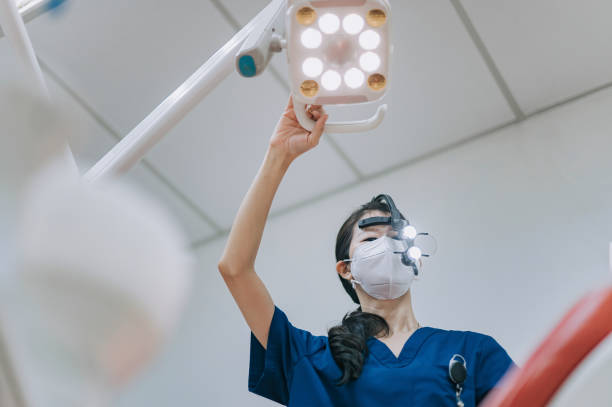 돋보기를 가진 아시아 중국 여성 치과 의사 환자에서 위에서보고있는 외과 적 빛을 조정하십시오. - medical exam dentist dentists chair dental assistant 뉴스 사진 이미지