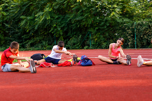 Group of teenage athletes stretching before training.
