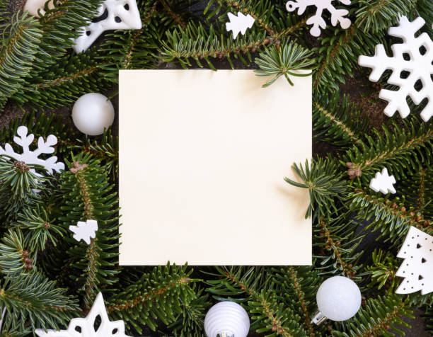 istock Square paper card between white Christmas decorations and green fir branches 1423897901