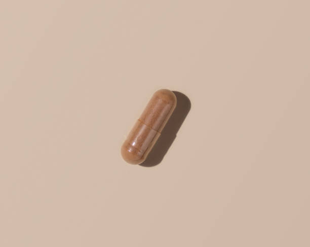 istock Brown Medical capsule on light beige top view, hard shadows. Taking dietary supplements 1423897914