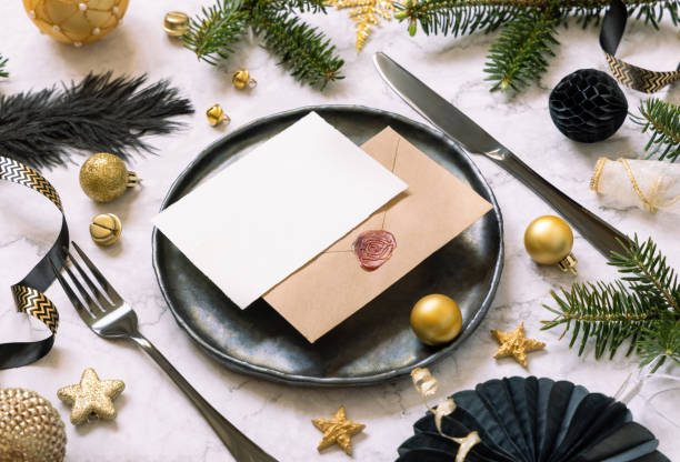 istock Black and golden Christmas Table setting with a card, ornaments and fir tree branches. Mockup 1423897926