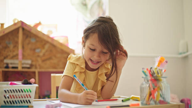 istock Little girl drawing while sitting at the table in her room 1423898466