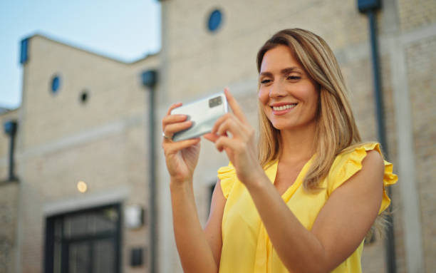 istock Beautiful woman taking pictures with her smartphone while exploring a city 1423899604