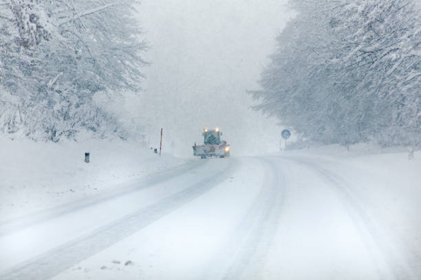 Snowplow cleaning ice cold frozen road during blizzard